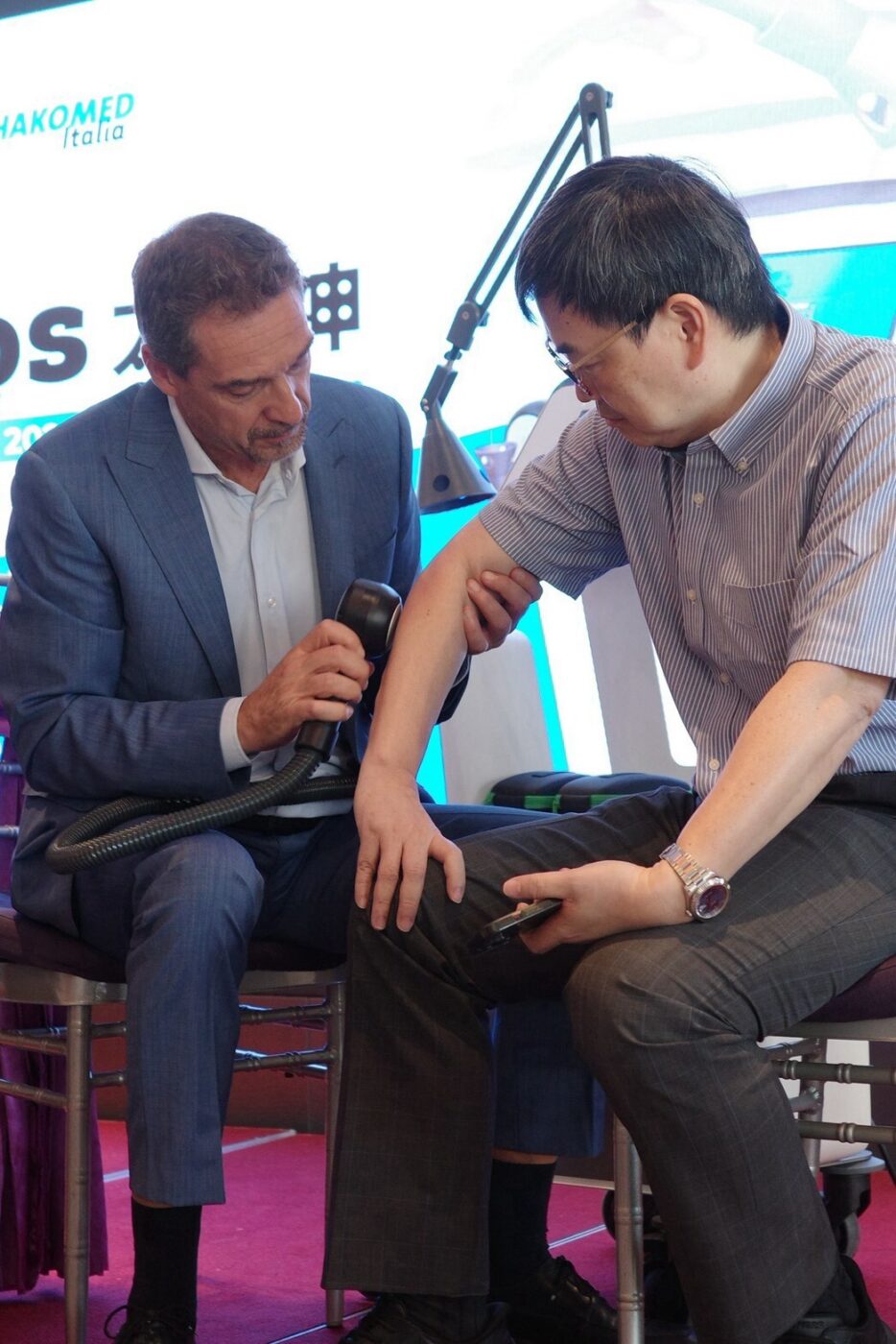 Dr. Maurizio Gioda demonstriert die Anwendung des qmd Hochleistungslasers helios am Arm eines Workshop-Teilnehmers in Taiwan.
